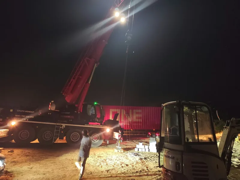 Grua preparada para elevar uma casa modular durante a noite